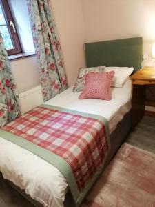 卡梅尔牡鹿&雉鸡旅馆的一间小卧室,配有一张带红色枕头的床