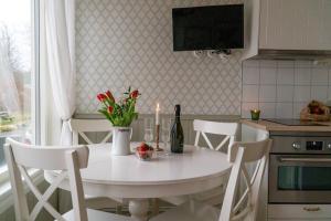 卢恩斯基尔Anfasteröd Gårdsvik - badstugor med loft的厨房配有白色桌子,提供一瓶葡萄酒和鲜花