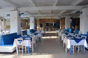 兰佩杜萨Villaggio La Roccia camping的用餐室配有蓝色桌子和白色椅子