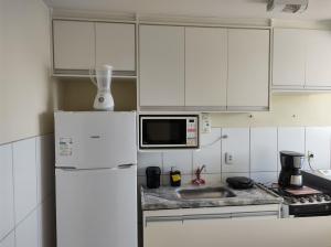 圣若泽杜斯坎普斯Apê - Parque Industrial - SJC - SP的厨房配有白色橱柜和白色冰箱。
