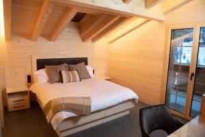 GsteigChalet mit Kino und Jacuzzi in Gsteig b. Gstaad的木制客房内的一间卧室,配有一张床