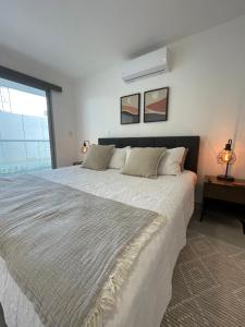 圣佩德罗-德马科里斯Exclusivo apartamento frente al mar的卧室配有一张大白色床和窗户