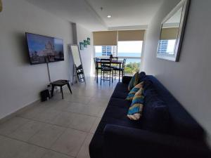 普拉亚科罗纳多Apartamentos en Playa Coronado的客厅配有蓝色的沙发和桌子