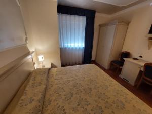 罗卡圣焦万尼美第奇别墅酒店的一间卧室配有一张床、一个窗口和一张书桌