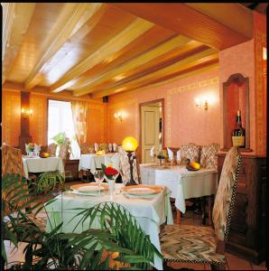 CérillyHotel Chez Chaumat的一间设有白色桌椅的餐厅和一间房间