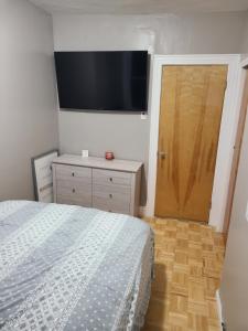 Woodsidecomfortable private apartment near Manhattan on train的卧室配有一张床,墙上配有电视