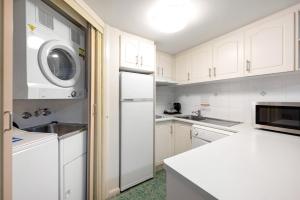 布里斯班飞马汽车旅馆及服务式公寓的厨房配有白色橱柜、洗衣机和烘干机