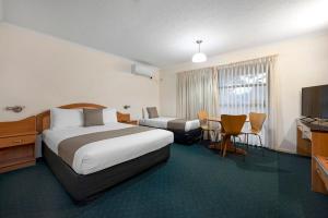 布里斯班飞马汽车旅馆及服务式公寓的酒店客房设有两张床和电视。