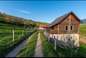 AndrijevicaHousehold Babovic - Old house Miljan's valley的土路旁田野的房子