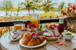 阿鲁坦加Tai Roto Bay的阳台上的桌子上摆着早餐食品和饮料