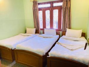 博卡拉HOTEL ICE VIEW POKHARA的带窗户的客房内的三张床