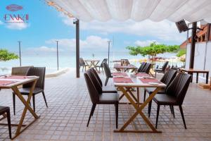 芭堤雅市中心ENNKAI Beachfront Resort Koh Larn的一间设有桌椅的海洋餐厅