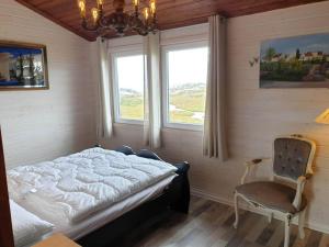 SkudeneshavnHoliday home skudeneshavn III的一间卧室配有一张床和一把椅子,还有两个窗户