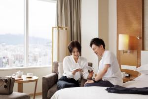 广岛广岛喜来登大酒店的坐在酒店房间床上的男女