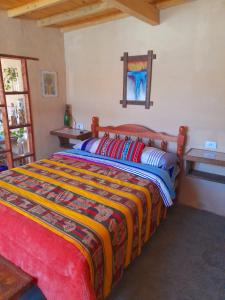 麦马拉Sumaj Rústica的一间卧室配有一张带彩色毯子的床