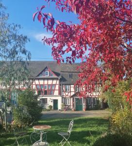 乎尔博赫Hof Idarwald的院子里有红色叶子的房子,配有桌子和椅子