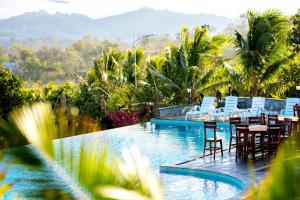 森莫诺隆KNN Luxury Hill的一个带桌椅的度假游泳池,以及山地背景