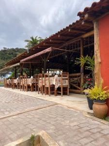 多明戈斯马丁斯Recanto da Roca的屋顶下设有桌椅的餐厅