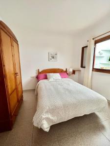 蓬塔穆赫雷斯Casa Los Jameos的一间卧室配有带粉红色枕头的床和窗户。