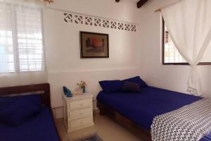通苏帕Casa Albatros (Playa-Esmeraldas)的一间卧室设有两张带蓝色床单的床和窗户。