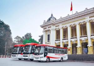 吉婆岛Nhat Mai Hotel的停在大楼前的两辆公共汽车