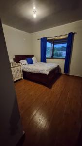 下博克特Vistaverdeboquete的一间卧室配有床和蓝色窗帘的窗户