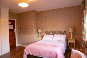 比尔The Ring Farmhouse的一间卧室配有一张带粉色毯子的床