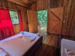 德雷克Citronela Lodge Corcovado的一间卧室设有一张床、一扇门和一扇窗户