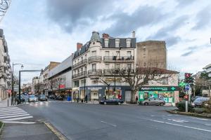 维勒蒙布勒MBA Splendide Appart - Le Raincy - Banlieue Paris的一条城市街道,有一座白色的大建筑,有汽车停放