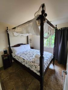 凯里凯里阿瓦隆度假村的一间卧室设有天蓬床和窗户。