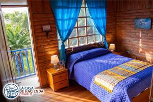 奥塔瓦洛La Casa de Hacienda的一间卧室配有一张带蓝色棉被的床和窗户。