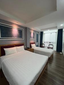 河内Holiday Suites Hotel & Spa的酒店客房,配有两张带白色床单的床