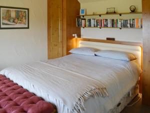 EdlinghamGarden Cottage的卧室配有白色的床和红色的搁脚凳