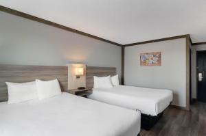 斯科茨布拉夫Econo Lodge Scottsbluff的配有白色床单的酒店客房内的两张床