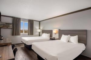 斯科茨布拉夫Econo Lodge Scottsbluff的酒店客房配有两张床和一张书桌