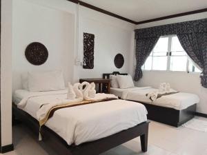清迈Vlodge House的一间卧室设有两张带白色床单的床和窗户。