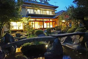 横滨日本庭園古民家　飯田屋　Traditional experience iidayajapan的一座花园,一座建筑前的池塘上方有一座桥梁
