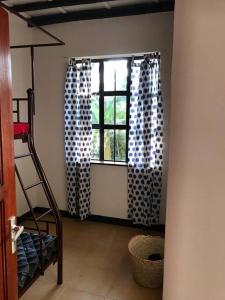 姆托瓦姆布The Hondo Hondo House, Mto wa Mbu的带窗帘和梯子的窗户的房间