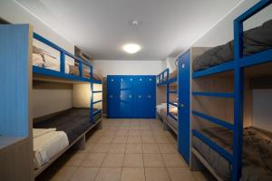 罗韦雷托Ostello Città di Rovereto的一间设有双层床和蓝色门的房间