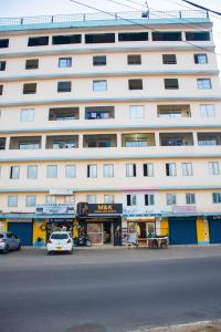 蒙巴萨IWACU-Cosy,Spacious 1 Bedroom Apartment along Nyali Road的一座白色的大建筑,前面有汽车停放