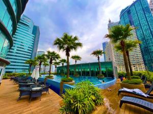 吉隆坡Vortex suites near by KLCC的棕榈树和长椅的城市游泳池