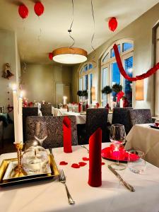 拉德博伊尔ZU DEN LINDEN - RADEBEUL Pension mit Restaurant的餐厅的一张桌子,上面有红色的装饰