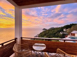 涛岛The AVA Resort Koh Tao的阳台配有桌椅,俯瞰着大海