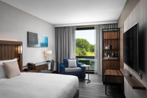 霍夫多普阿姆斯特丹机场万怡酒店的酒店客房配有一张床、一把椅子和一台电视。