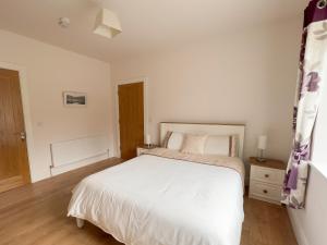 特里姆Woodview Lodge的卧室配有白色的床,铺有木地板