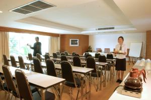 曼谷班萨柏国际青年旅舍的站在带桌椅的房间的妇女