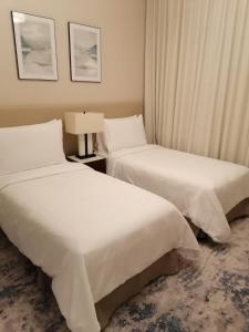 SharmTwo Bedrooms Apartment at Address Residence Fujairah的配有白色床单的酒店客房内的两张床