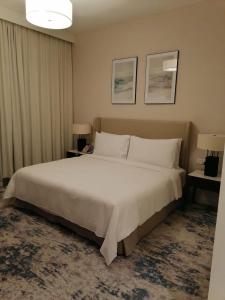 SharmTwo Bedrooms Apartment at Address Residence Fujairah的卧室配有一张白色大床和两盏灯。