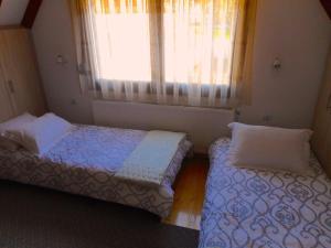 MikrolímniThe Lake House的一间卧室设有两张床,窗户配有窗帘