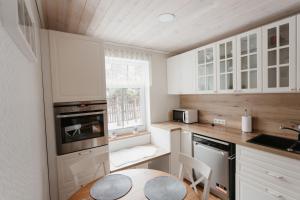塔尔图Vase Holiday Home的厨房配有白色橱柜、桌子和窗户。